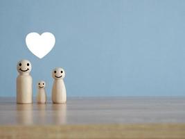 Wooden puppet family on wooden table with white heart icon photo