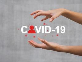 Woman's hand showing COVID-19 message with red human infection icon. photo