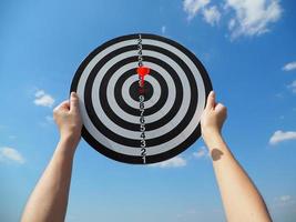 hand of a business woman holding a target business success business idea red dart in the center up in the sky photo