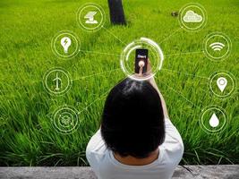 Young woman's hand holding a smartphone showing concept of sustainable renewable energy, environmentally friendly and carbon reduction initiatives. There is light inside the picture. photo