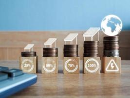 Wooden blocks on stacked coins with energy saving icons. with solar cells The use of renewable energy is environmentally friendly. photo