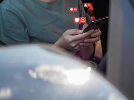 joven mujer jugando social medios de comunicación en su teléfono inteligente en el coche. foto