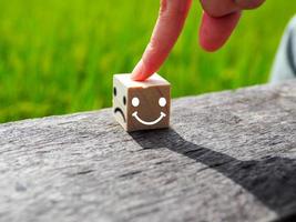 sonriente y triste cara icono en de madera bloquear, positivo pensando selección contento parte selección verde naturaleza antecedentes foto