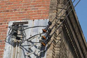 Power line cables on the red brick and blue sky background photo