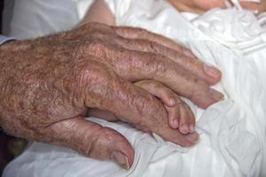 old retired man hands holding newborn infant one photo