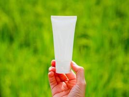 white skin care cream tube nature background green rice field Gentle on the skin, face and body care natural extracts photo