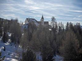 iglesia en monte croce dolomitas valle de badia montañas en invierno nieve panorama foto