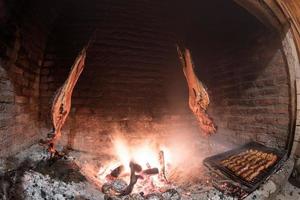 Asado cooking in ancient fireplace photo