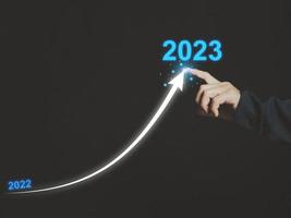 Arrow from 2022 to 2023. Businessman drawing line arrows from 2022 to 2023. Business startup. New concept. New style of operation in the coming year. photo