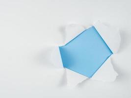 Torn white paper with holes on blue background for advertising or promotional content show your products photo