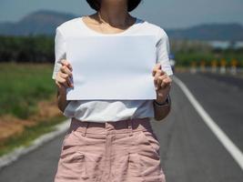 woman holding white paper On the road. Space for advertising. copy space photo