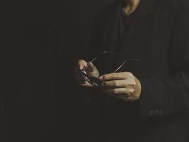 businessman holding glasses in hand on a black background photo