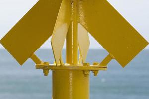 Yellow no sail metallic buoy on blue sea background photo