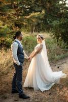 the groom and the bride are walking in the forest photo