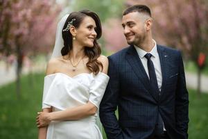 newlyweds walk in the park among cherry blossoms photo