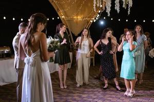 bride in a white dress throws a wedding bouquet photo