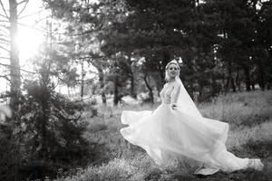 bride blonde girl with a bouquet in the forest photo