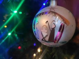 bola de navidad hecha a mano de vidrio en el detalle del árbol de navidad luces borrosas foto