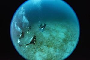 scuba diver near boat in transaprent waters view from submarine porthole photo