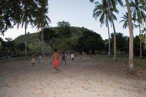 GILI ASAHAN, INDONESIA - AUGUST, 22 2016 - boys are playing soccer at sunset on a palm tree field near the beach photo