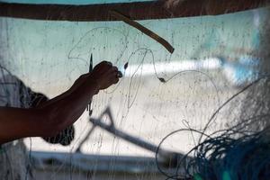 Fisherman hand repairing fishing net detail photo