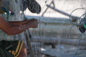 Fisherman hand repairing fishing net detail photo