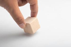 Hand holding a wooden block with a question mark on a white background photo