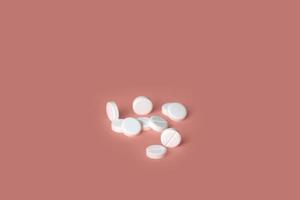 Group of white medical pills isolated on pink background. selective focus. concept of health photo