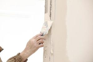 Builder using a trowel to add plaster. Plastering wall with putty-knife, close up image. Fixing wall surface and preparation for painting. construction work during quarantine photo