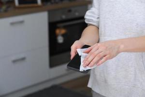 Woman disinfecting phone with antiseptic wet wipe. Antiseptic napkin to prevent spread of germs, bacteria and coronavirus. Coronavirus prevention. Prevent illness coronavirus after public place. photo