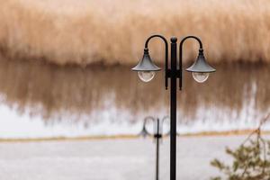 Black iron retro style street lantern in front of the park and river photo