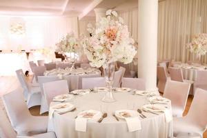 festive wedding decoration. Beautiful fresh white and pink flowers in glass vase on dining table on wedding day. High quality photo