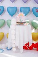 big Birthday cake with rainbow, colorful Sprinkles. on many colorful heart balloons background. birthday party. sweet holiday.