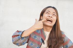 asiático mujer teniendo comida atascado en su dientes foto