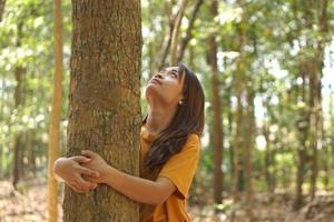 concepto de ahorro el mundo asiático mujer abrazando un árbol foto