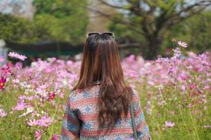 contento asiático mujer en cosmos flor jardín foto