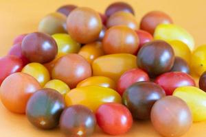 Cherry tomatoes in a variety of bright colors on an orange background. photo