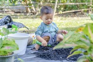 Little child shovels soil into pots to prepare plants for planting. Toddler boy digging soil for planting to Mother's little helper. Gardening. Hobbies at home horticulture. Leisure activities concept photo