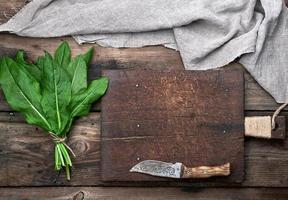 manojo de hojas verdes frescas de acedera y tabla de cortar marrón vieja foto