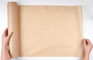 roll of brown parchment paper for baking food in female hands photo