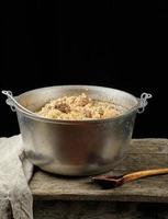 Pilaf is an oriental dish of boiled rice with fat and slices of meat and spices. the dish is cooked in a large aluminum cauldron photo