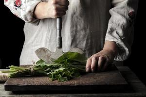 woman in a gray linen dress is cutting green leaves of fresh sorrel photo