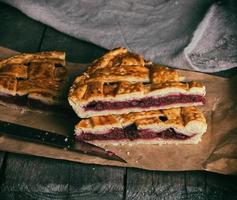 baked pieces of cake with cherries lie on brown paper photo