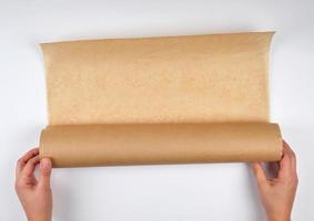 two hands hold a large roll of brown parchment paper photo