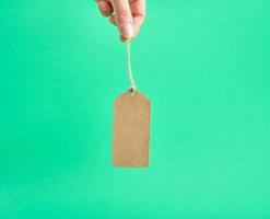 female hand holding a paper brown blank tag on a rope photo