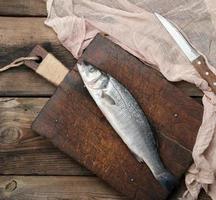 fresh whole sea bass fish on brown cutting board photo