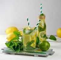 bebida refrescante de verano limonada con limones, hojas de menta, lima en un vaso foto