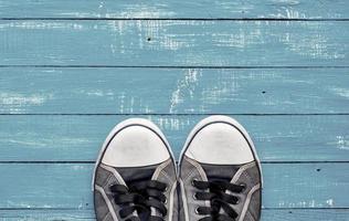 Blue men's old shabby sneakers on a blue wooden surface photo