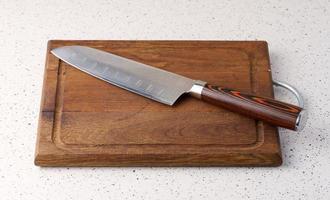 Empty wooden cutting board and kitchen knife on the table, top view photo
