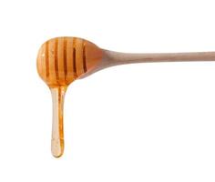 Flowing drops of yellow honey from a wooden stick on a white isolated background photo